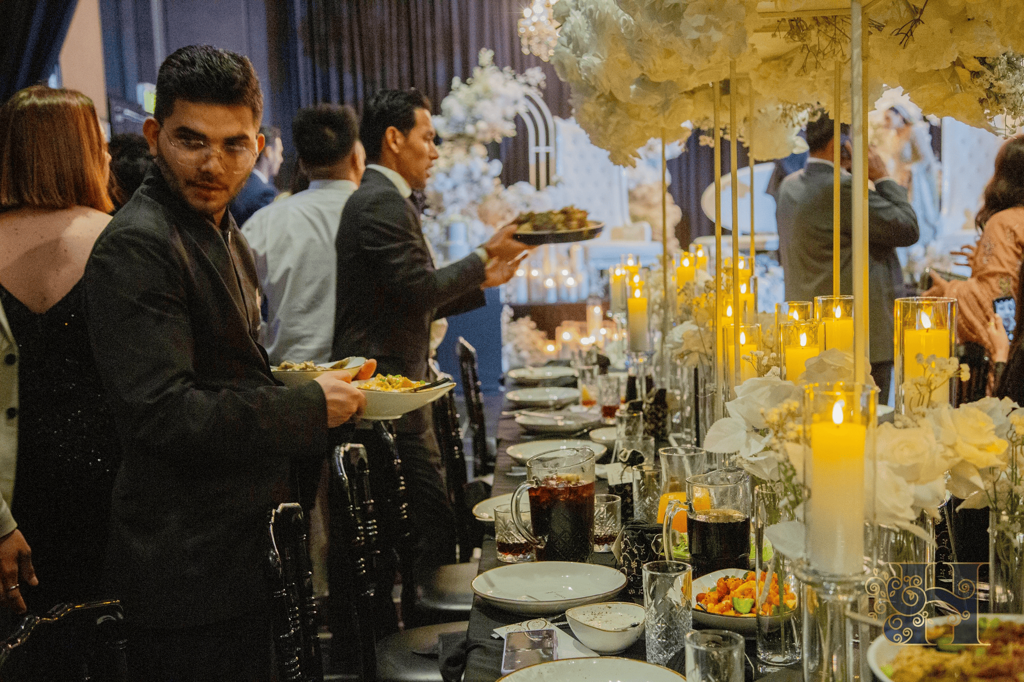 People enjoying a standing buffet-style dinner, gathered around tables filled with assorted dishes.